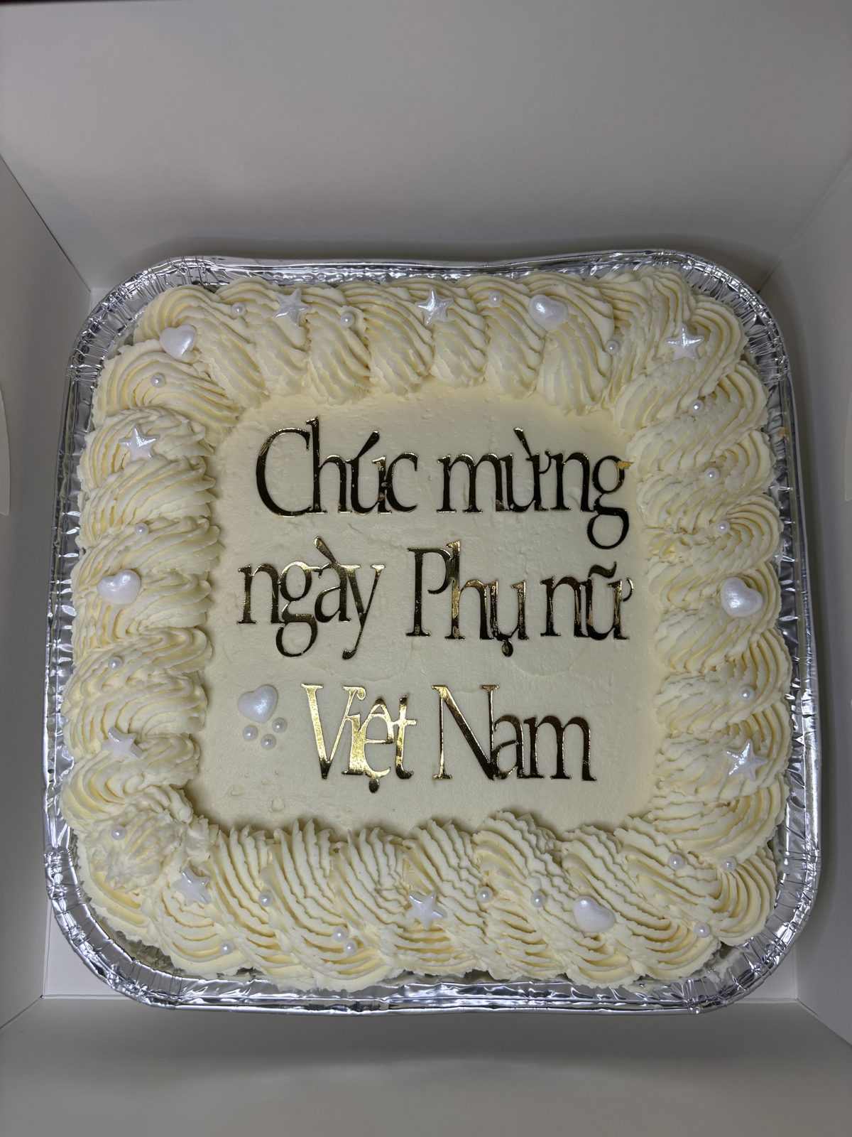 Square cheesecake with a piped buttercream border, pearls and a gold Chúc mừng ngày Phụ nữ Việt Nam topper for Vietnamese Women&rsquo;s Day